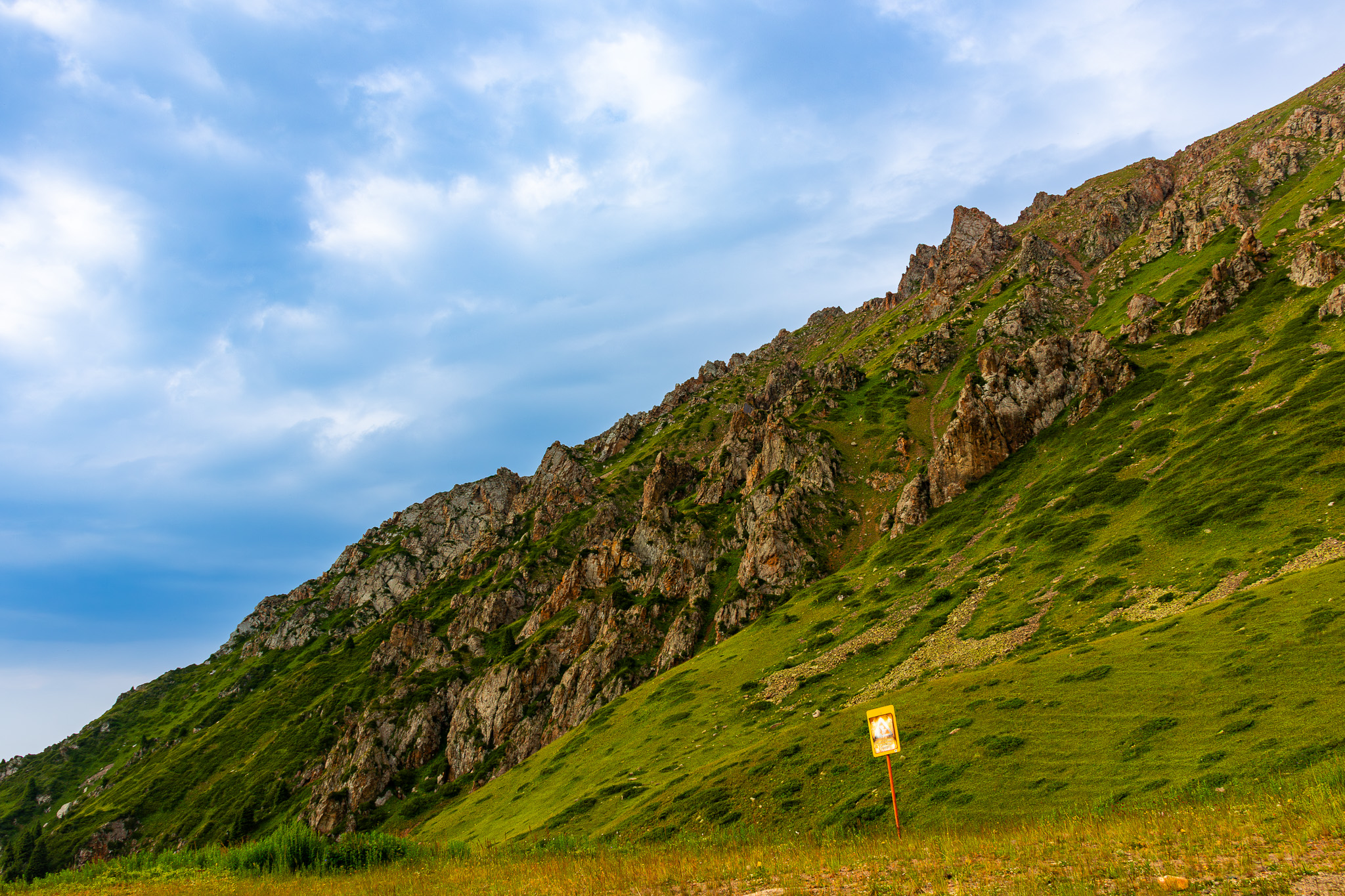 A rocky mountain landscape split by diagonal with the left being the blue sky and the right a slope of a mountain