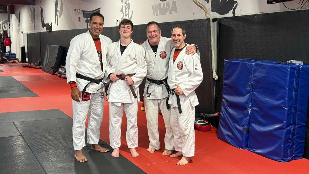 Daniel and his judo coaches pose for a photo celebrating his judo promotion to brown belt